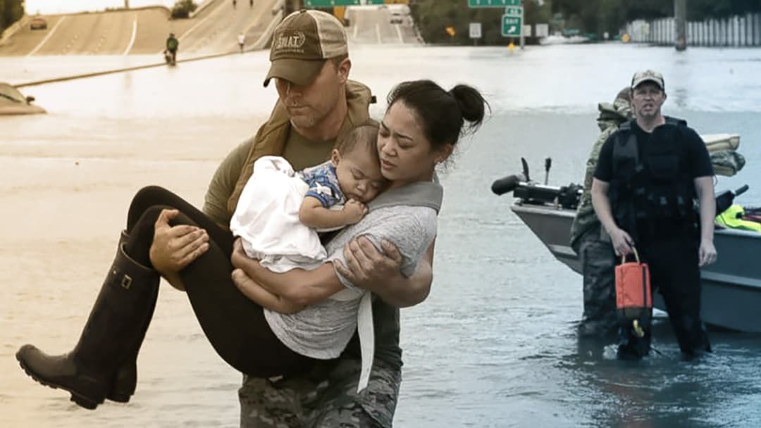 A man carries a woman and her baby above a flooded street.