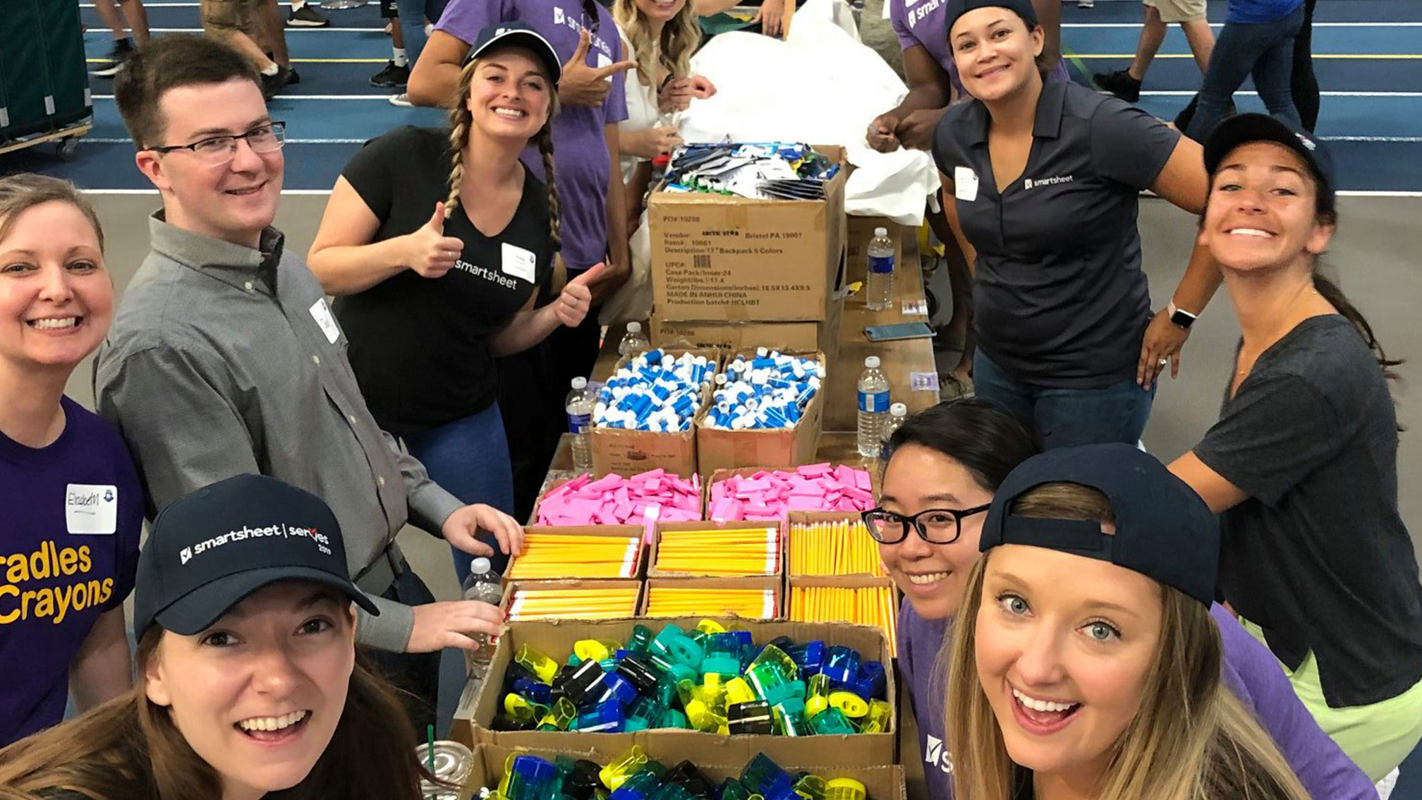Smartsheet employees pose for a group photo as they surround boxes of supplies at a volunteering event.